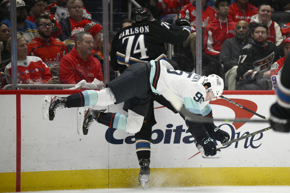 Washington Capitals defenseman John Carlson (74) and Seattle Kraken left wing Andre Burakovsky (95) collide along the boards during the second period of an NHL hockey game Friday, Dec. 9, 2022, in Washington. (AP Photo/Nick Wass)