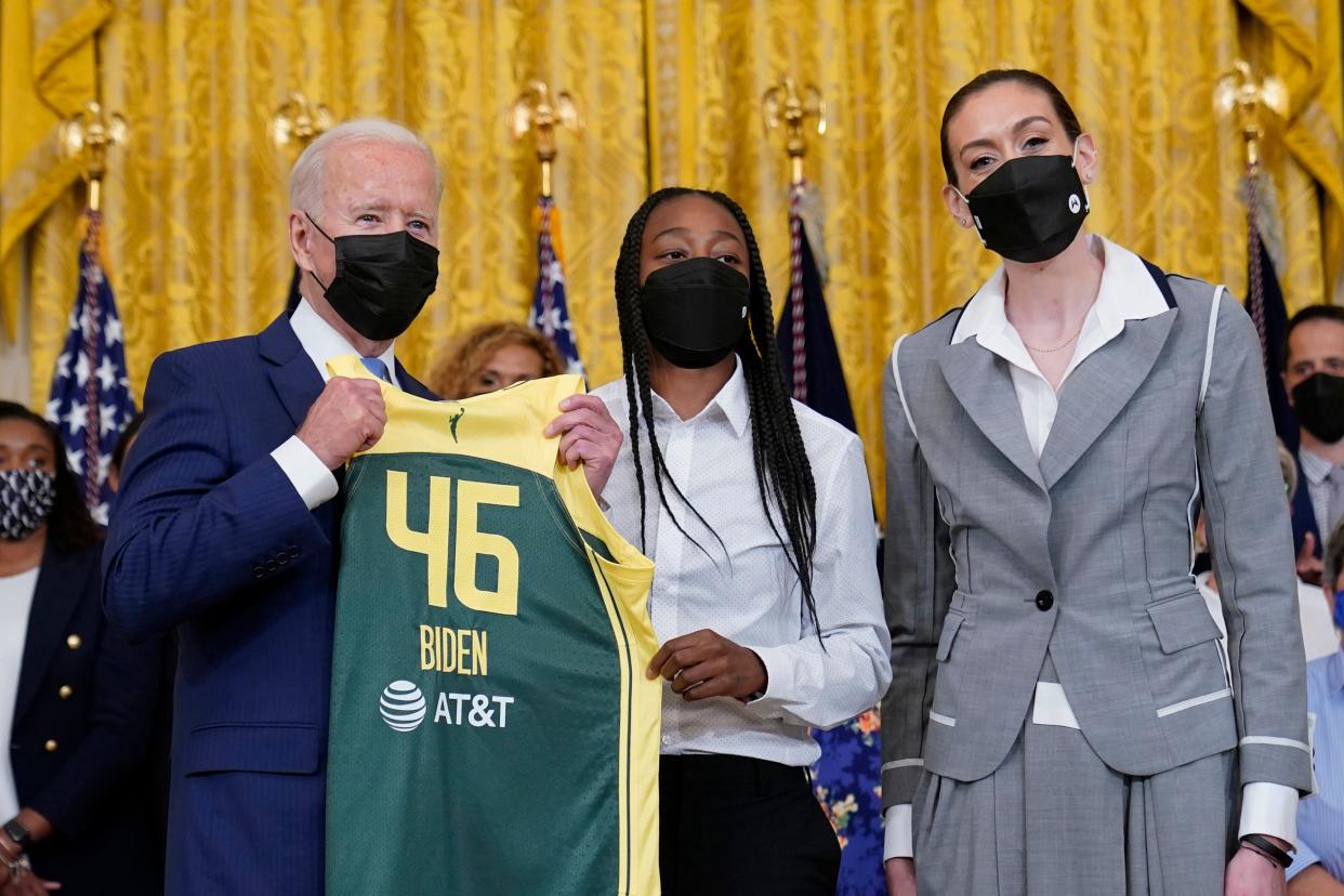 President Joe Biden, left, poses for a photo with Seattle Storm's Jewell Loyd, center, and Breanna Stewart, right, during an event in the East Room of the White House in Washington, Monday, Aug. 23, 2021, to celebrate their 2020 WNBA Championship. (AP Photo/Susan Walsh)