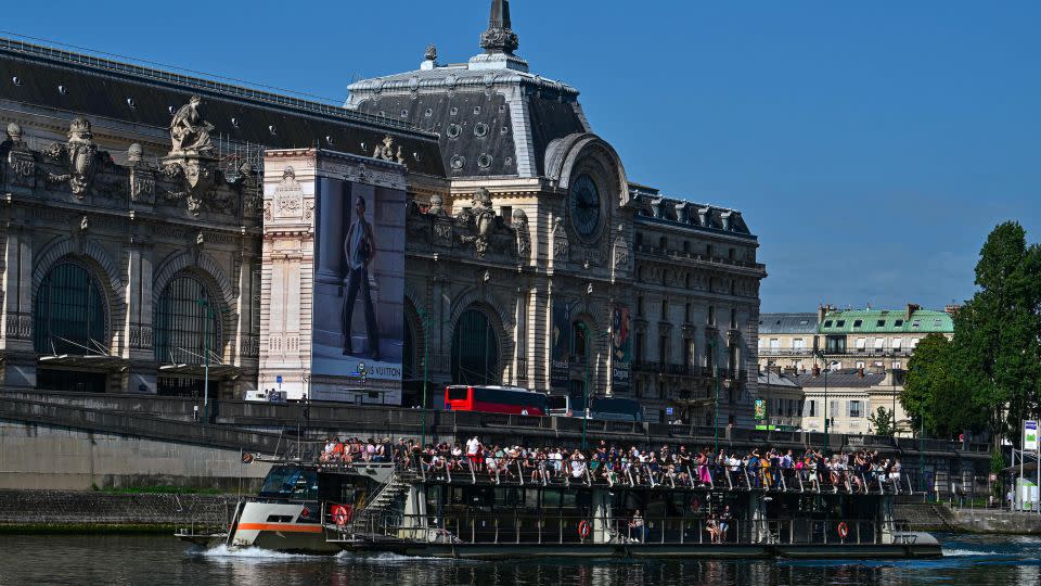 Tourists tour Paris aboard an open excursion boat on the Seine, with the Musee d'Orsay in the background, on August 22, 2023. - Miguel Medina/AFP/Getty Images