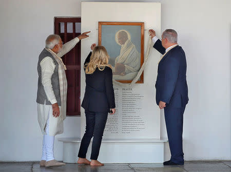 Israeli Prime Minister Benjamin Netanyahu and his wife Sara tie a garland made of cotton threads to the portrait of Mahatma Gandhi as India's Prime Minister Narendra Modi looks on during their visit to Gandhi Ashram in Ahmedabad, India, January 17, 2018. REUTERS/Amit Dave