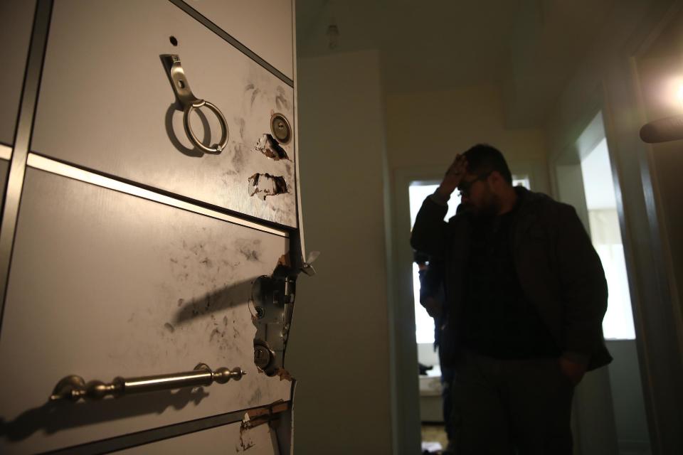 A plainclothes police officer stands beside the door of a flat, damaged during an overnight police raid to arrest a suspect of New Year's Day nightclub attack, in Istanbul, Tuesday, Jan. 17, 2017. Turkish police said they captured the gunman who carried out the deadly New Year's nightclub attack in Istanbul, with officials saying Tuesday that he's an Uzbekistan national who trained in Afghanistan and confessed to the massacre.(AP Photo/Lefteris Pitarakis)