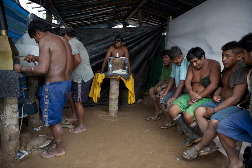 In this May 3, 2014 photo, wildcat miners wait their turn to melt their amalgam of gold and mercury to burn off the mercury in the temporary home of a gold buyer in La Pampa in Peru's Madre de Dios region. It's not just miners who are threatened with economic catastrophe from the government¹s campaign to wipe out illegal mining operations, said a mining camp cook. For every miner there is a family that eats because he works, she said. (AP Photo/Rodrigo Abd)