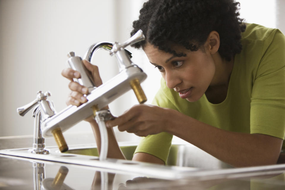 woman using a wrench to fix her own kitchen sink