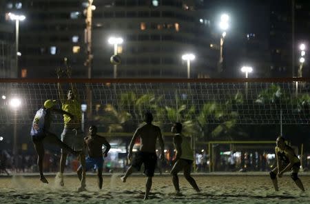 Residents play beach volleyball during at night on Copacabana beach, where the Olympic beach volleyball will take place in Rio de Janeiro, Brazil, July 9, 2015. REUTERS/Sergio Moraes