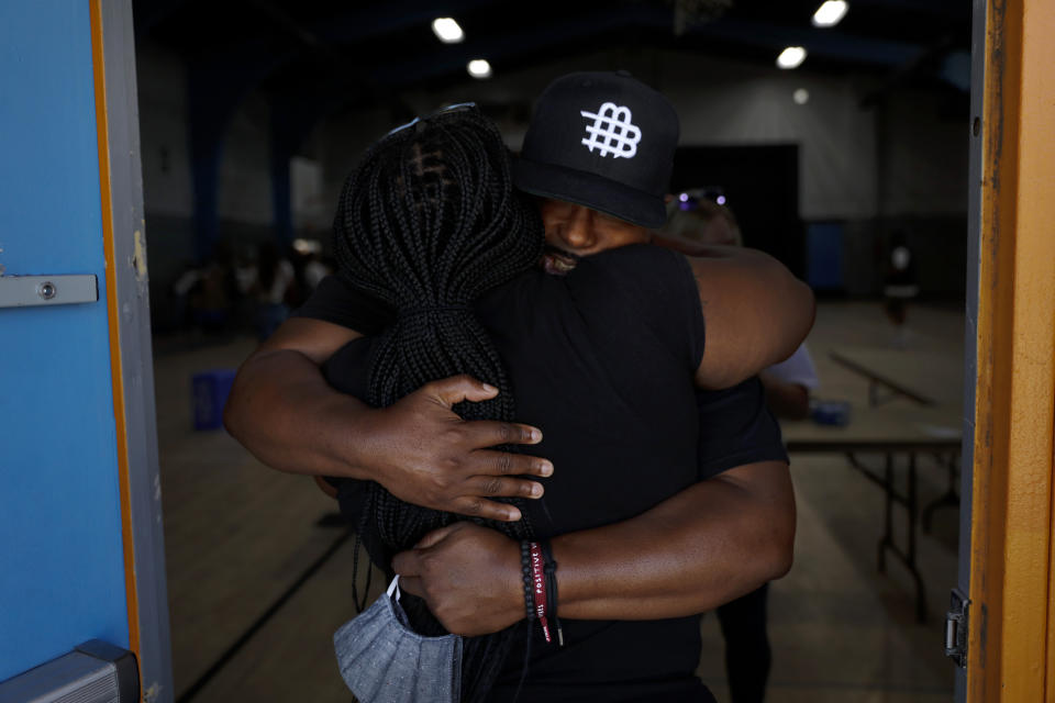 Think Watts Foundation's Sheldon Lewis, facing camera, hugs volunteer Tanya Dorsey after attending a community event held to give out free food to tenants living in the Nickerson Gardens housing project in the Watts neighborhood of Los Angeles, Wednesday, June 10, 2020. (AP Photo/Jae C. Hong)