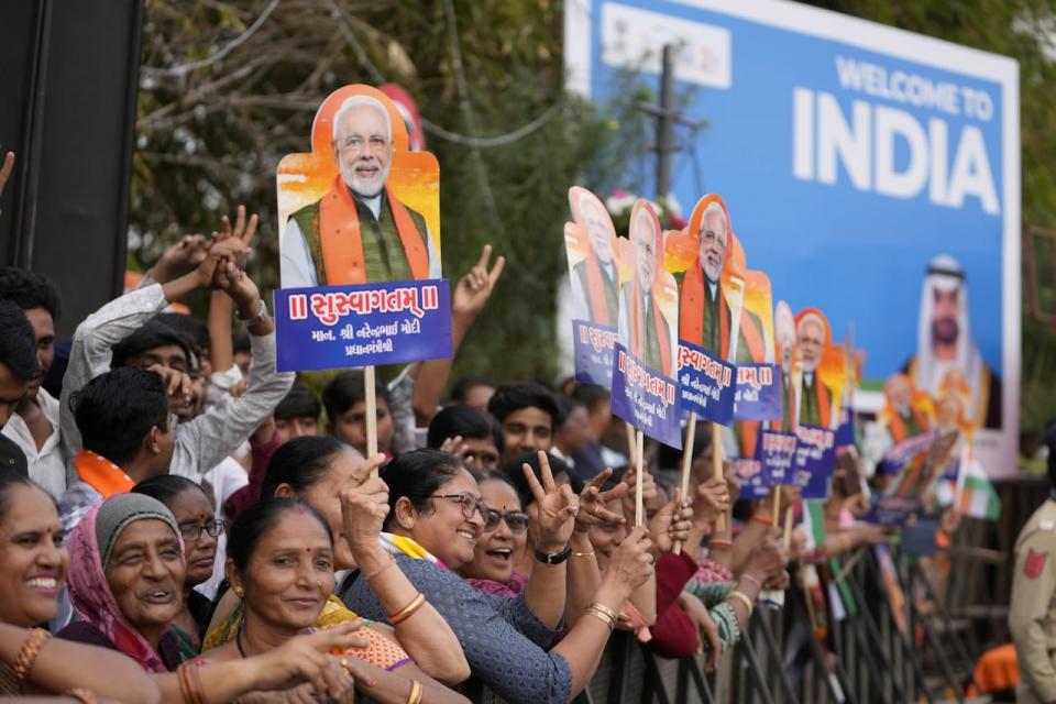 People hold portraits of Indian prime minister Narendra Modi and waits for a road show by Modi and President of the United Arab Emirates Sheikh Mohamed bin Zayed Al Nahyan, in Ahmedabad, India, Tuesday, Jan. 9, 2024.  