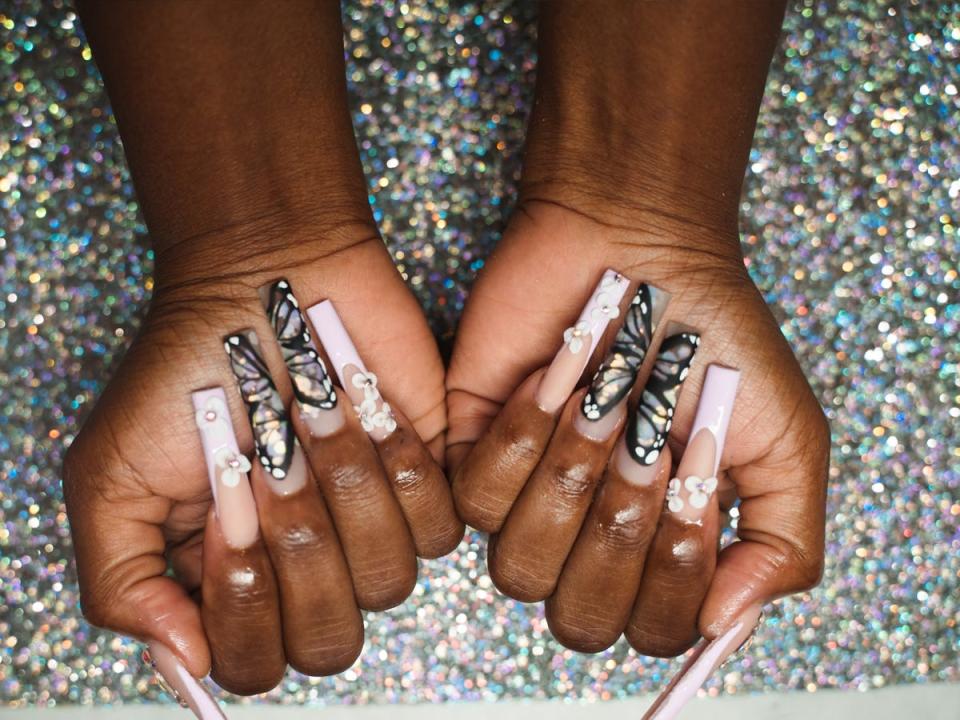 Nails with butterfly accents and pearls.