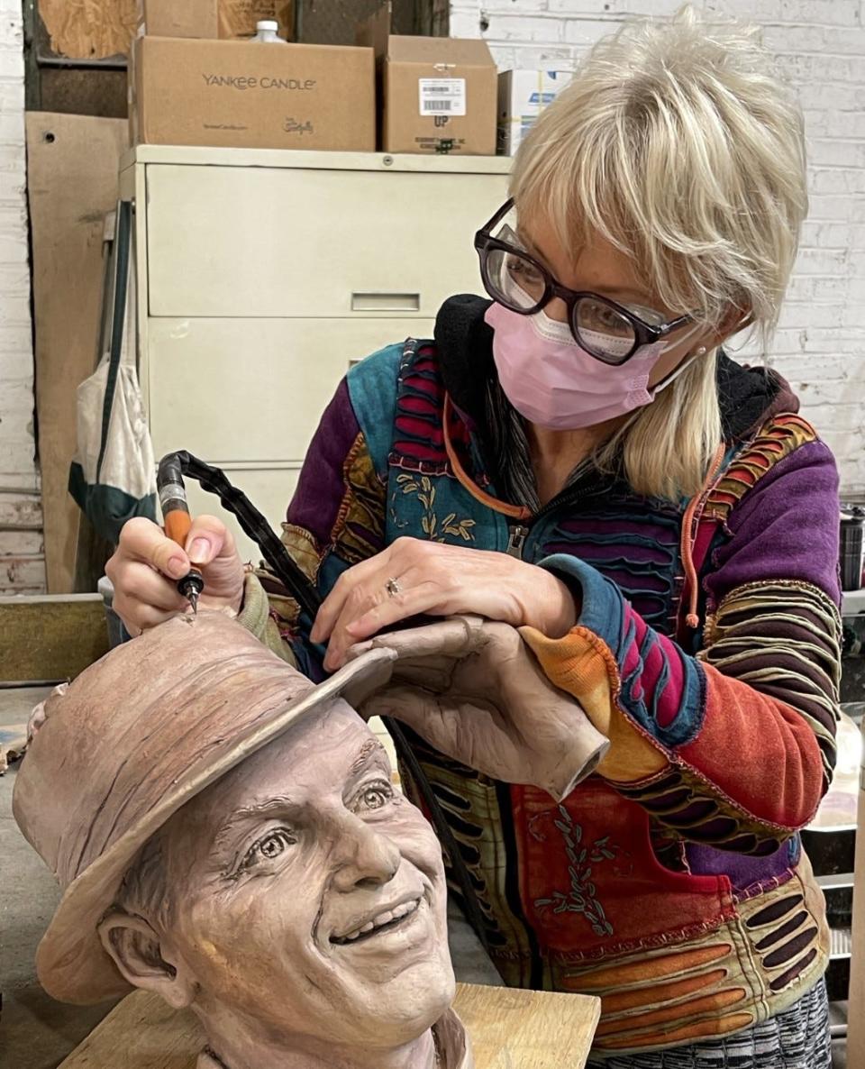 Carolyn Palmer applies finishing touches to the bronze cast of Sinatra's face and hand in her studio.  The statue is cast in pieces, and then assembled.