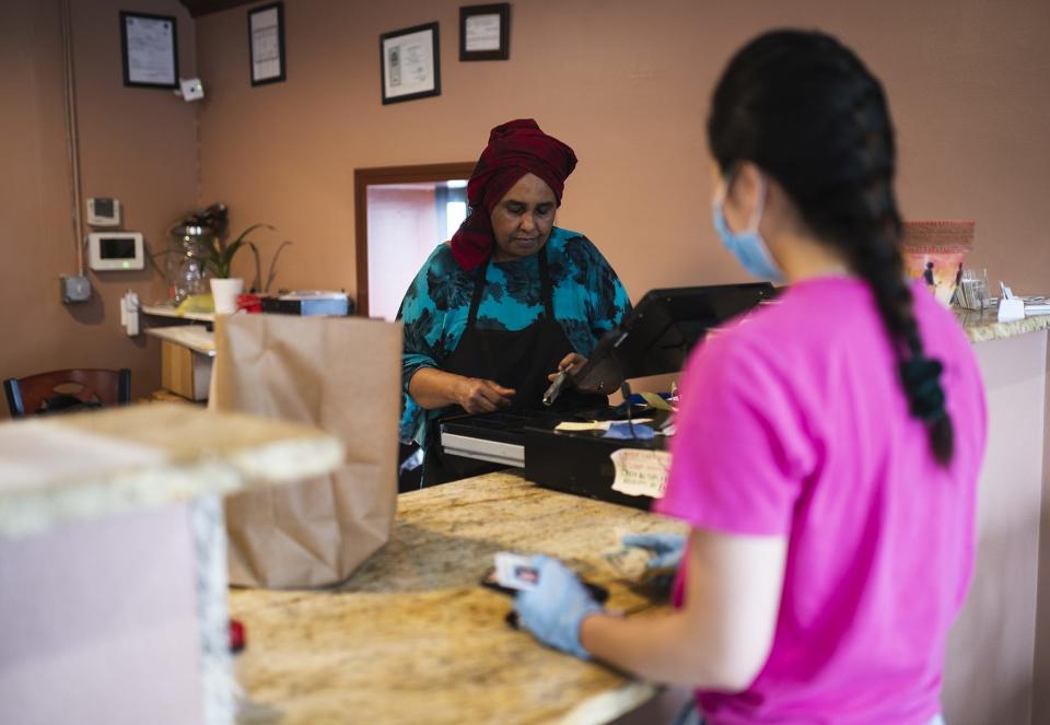 Fatima Mohamed, left, cashes out Nellie Zahng as she picks up an order from Fatima's Cafe in Worcester, one of six local restaurants to receive $5,000 from the Massachusetts Conference of Women.