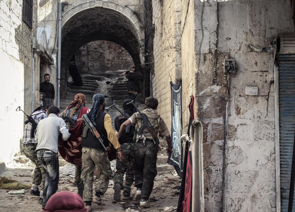 FILE - In this Tuesday, Oct. 30, 2012 file photo, a group of Free Syrian Army fighters carry a wounded comrade to cover in the town of Harem, Syria. A sharp increase in the number of al-Qaida linked fighters joining the fight against President Bashar Assad in Syria is threatening to spill over the borders and prompting the Jewish state to re-evaluate its policy of neutrality in the civil war next door, a senior Israeli intelligence official warned on Friday, Jan. 24, 2014. (AP Photo/Mustafa Karali, File)