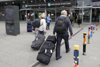 Foreign tourists arrive outside the Christchurch Airport terminal as they prepare to check in for a charter flight back to Germany via Vancouver from Christchurch, New Zealand, Monday, April 6, 2020. The German Embassy in Wellington last week said more than 12,000 German tourists had signed up for its repatriation program from New Zealand following the strict monthlong lockdown, which is aimed at preventing more coronavirus infections. The new coronavirus causes mild or moderate symptoms for most people, but for some, especially older adults and people with existing health problems, it can cause more severe illness or death. (AP Photo/Mark Baker)