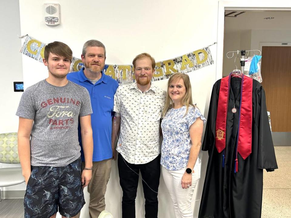 The Martin family, from left, Connor, Phil, Grant and Amy, pose with Grant’s graduation gown May 25, 2024, at Emory University Hospital in Atlanta, where Columbus State University conducted a special graduation ceremony for Grant, who is hospitalized while waiting for a heart transplant.