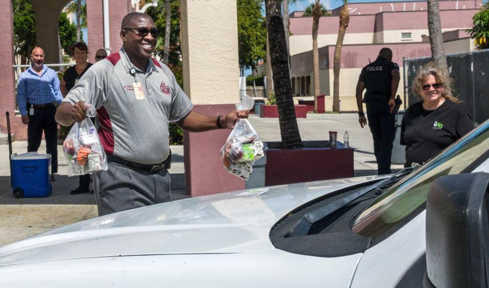 Lake Worth High School principal Elvis Epps carries free breakfasts and lunches to a parent in 2020. Epps announced his retirement this summer.