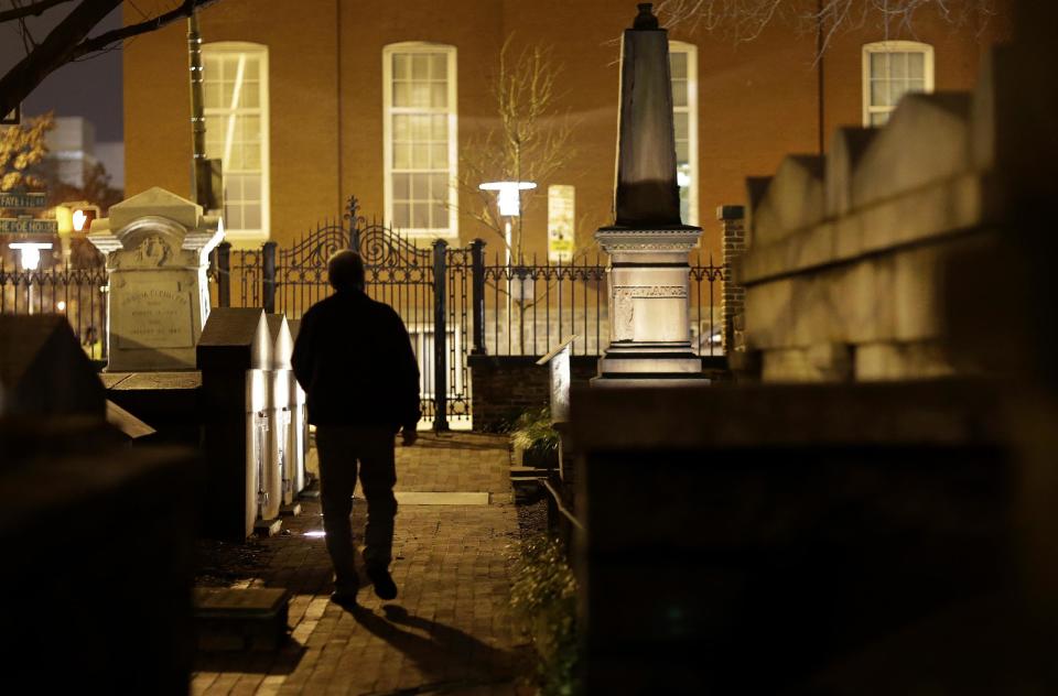 In this Jan. 15, 2013 photo, Jeff Jerome walks in a cemetery that is home to Edgar Allan Poe's grave in Baltimore. For years, Jerome watched as a mysterious man known as the Poe Toaster left three roses and an unfinished bottle of cognac at Poe’s grave every year on the legendary writer’s birthday. His identity is a great modern mystery, and just as mysteriously, the tradition ended four years ago. (AP Photo/Patrick Semansky)