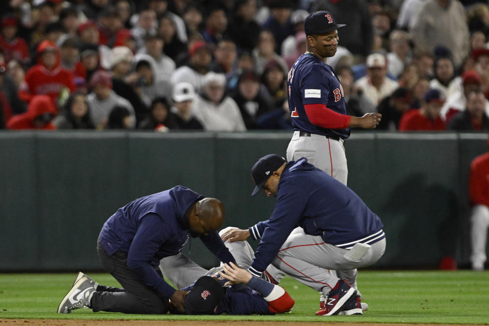 Trevor Story, campocorto de los Medias Rojas de Boston, recibe atención de un médico y del manager Alex Cora, tras lastimarse en el encuentro del viernes 5 de abril de 2024, ante los Angelinos de Los Ángeles (AP Foto/Alex Gallardo)