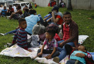 Freddy Rivas (segundo por la derecha), natural de Tocoa, Honduras, sus hijos Josué (izquierda) y Elkin (centro) y su hermano Mario esperan la llegada de más migrantes a una caravana que viajará hacia la frontera de Estados Unidos, en San Pedro Sula, Honduras, el 14 de enero de 2019. (AP Foto/Delmer Martinez)