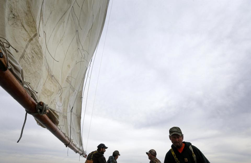 In this Dec. 20, 2013 picture, crew members Shawn Sturgis, from left, Kurt Pittman, Ted Williams Daniels and Danny Benton chat as they sail aboard the skipjack Hilda M. Willing in Tangier Sound near Deal Island, Md. (AP Photo/Patrick Semansky)