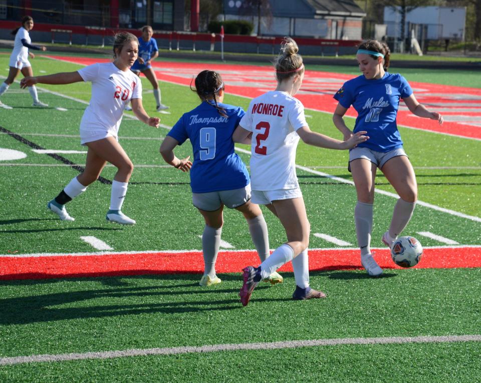 Brooke Trouten and Becca Pace of Monroe converge on the ball along with Madalyn Thompson and Presley Napier of Bedford during a 3-0 Monroe victory Tuesday. Bedford was wearing blue for Autism Awareness Day.