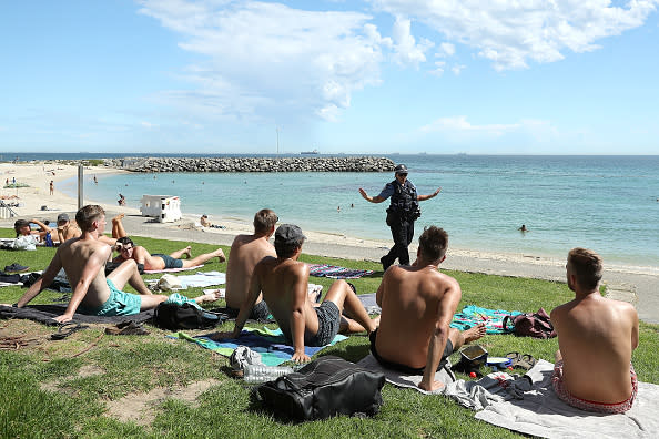 A police officer encourage beachgoers to keep a 1.5-metre social distance in Perth, Australia.