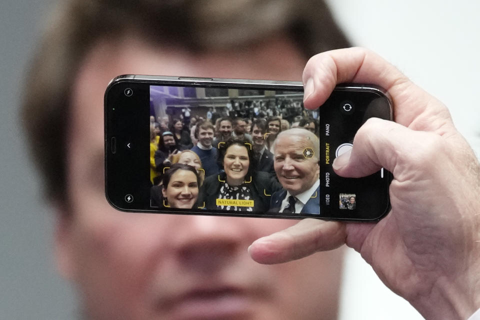 President Joe Biden holds a cellphone as he takes a picture with a members of the audience after making a speech about Northern Ireland's vast economic potential at the Ulster University's new campus in Belfast, Northern Ireland, Wednesday, April 12, 2023. President Biden is in Northern Ireland on Wednesday to participate in marking the 25th anniversary of the Good Friday Agreement, which brought peace to this part of the United Kingdom, as a new political crisis tests the strength of that peace. (AP Photo/Christophe Ena)