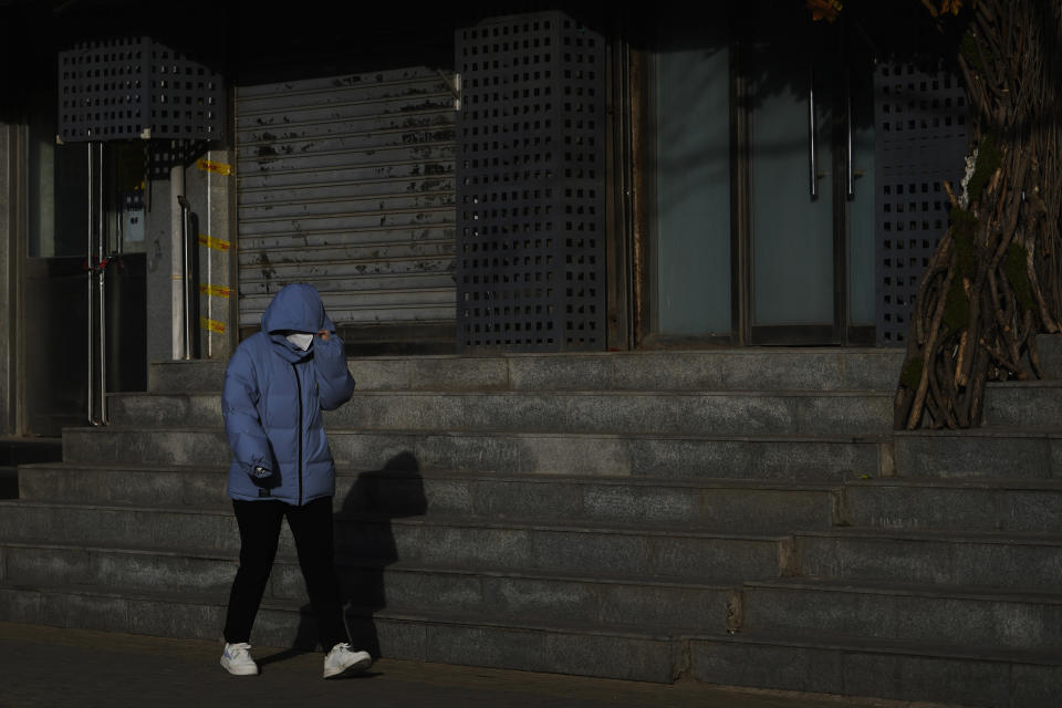 A resident wearing a face mask walks by shuttered business shops in Beijing, Tuesday, Jan. 17, 2023. China’s economic growth fell to 3% last year under pressure from antivirus controls and a real estate slump but is gradually reviving after restrictions that kept millions of people at home were lifted. (AP Photo/Andy Wong)