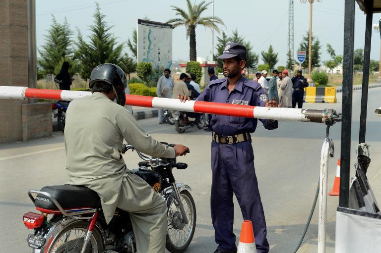 A Pakistani private security guard of the Bahria Town development stops a vehicle at a checkpoint at the main entrance in Rawalpindi on October 2, 2013