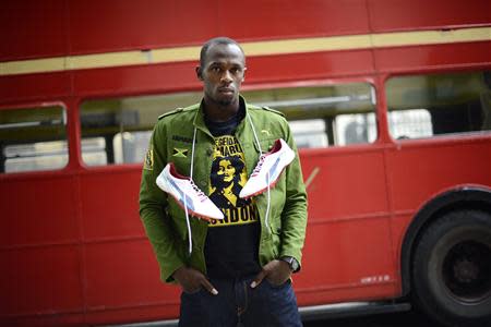 Sprinter Usain Bolt of Jamaica poses with his running spikes and official team uniform for the London 2012 Olympic Opening Ceremony during a photo shoot, arranged by sponsors Puma, beside a traditional routemaster bus outside the British Museum in London, in this June 1, 2012 file photograph. REUTERS/Dylan Martinez/Files