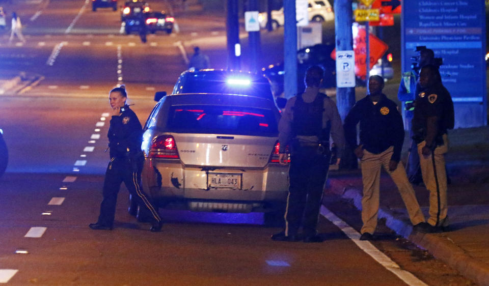 Lawmen and women from various agencies, gather around the front of the parking garage at the University of Mississippi Medical Center in Jackson, Miss., Thursday, Nov. 29, 2018. Two young children were shot Thursday in a car being driven by their mother near the University of Mississippi Medical Center, prompting the mother to pull them from the car and run them to the emergency room. (AP Photo/Rogelio V. Solis)