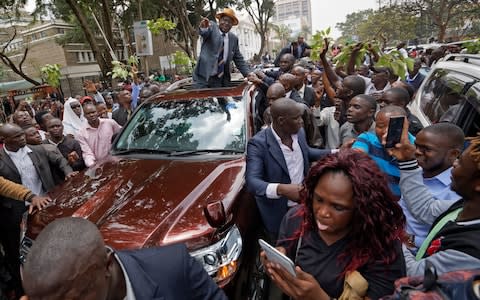 Opposition leader Raila Odinga smiles and waves to a crowd of his supporters as he leaves the Supreme Court in downtown Nairobi - Credit: Ben Curtis/AP