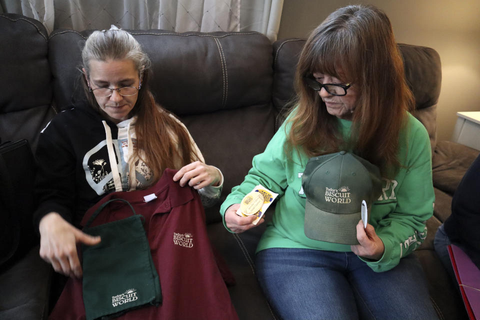 Former Tudor's Biscuit World employee Jennifer Patton, left, and current employee Cynthia Nicholson, right, show off their Tudor's Biscuit World uniforms and United Food & Commercial Workers Local 400 union stickers during an interview at Nicholson's Elkview, W.Va. home on Jan. 20, 2022. Patton said she was retaliated against and fired by management after she joined efforts to unionize the restaurant. Employees at the Elkview, W.Va., restaurant have already case ballots to decide whether or not they want to create a union. The votes will be read Tuesday. (AP Photo/Leah M. Willingham)