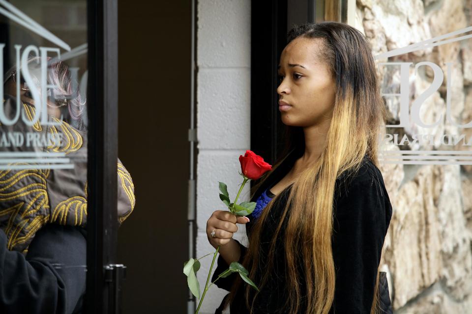 A mourner holds a rose while attending the funeral service for shooting victim Renisha McBride in Detroit