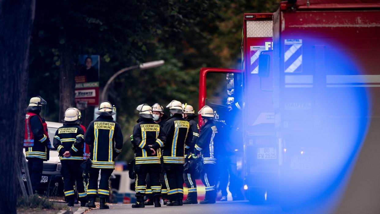 Feuerwehrleute stehen auf der gesperrten Volksgartenstraße in Dortmund beim Einsatz im Zusammenhang mit der Wohnungsdurchsuchung.