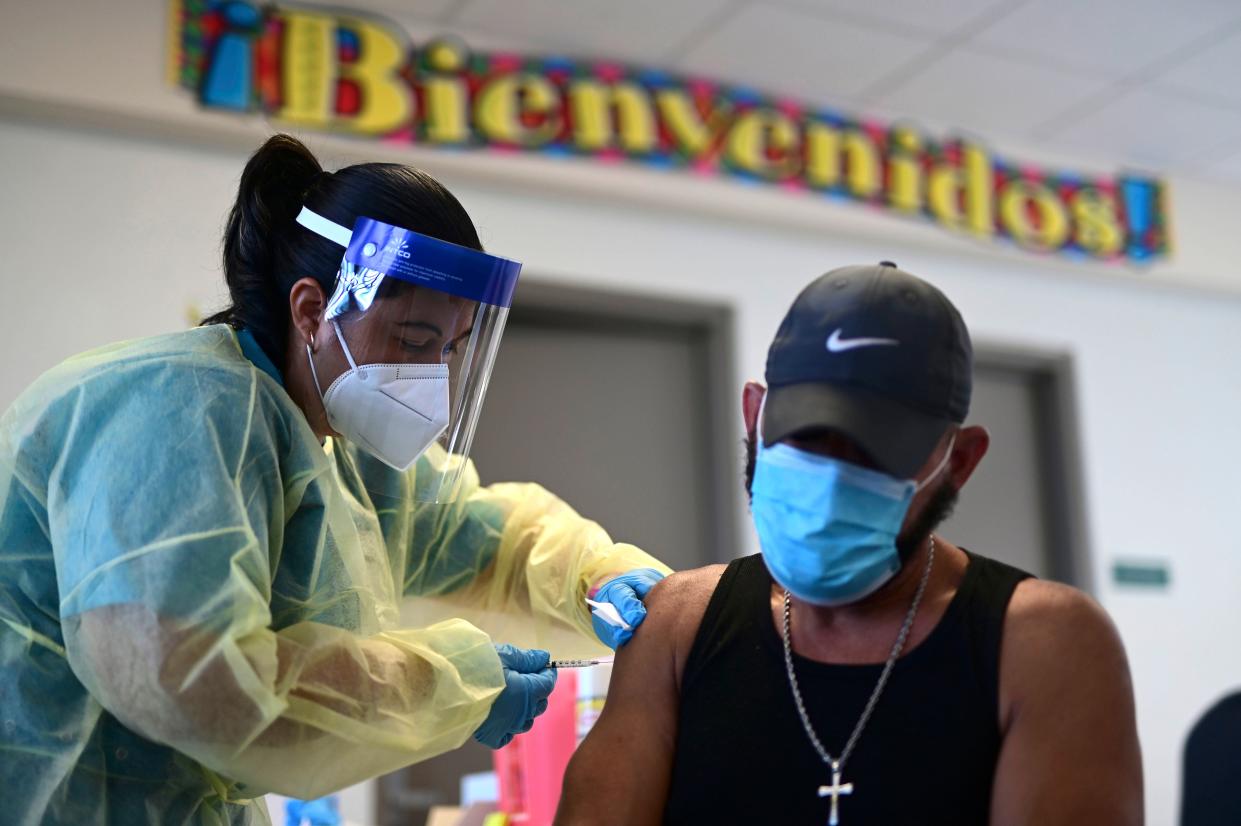 A healthcare worker is pictured injecting a man with a Moderna COVID-19 vaccine dose during a mass vaccination campaign at María Simmons School in Vieques, Puerto Rico.