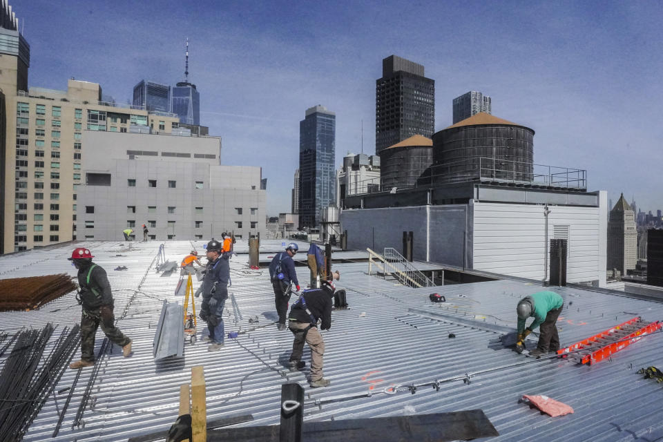 Construction workers update the roofing on a high rise at 160 Water Street in Manhattan's financial district, for the building's conversion to residential apartments, Tuesday, April 11, 2023, in New York. A growing number of developers are considering converting empty office towers into housing as part of an effort to revive struggling downtown business districts that emptied out during the pandemic. (AP Photo/Bebeto Matthews)