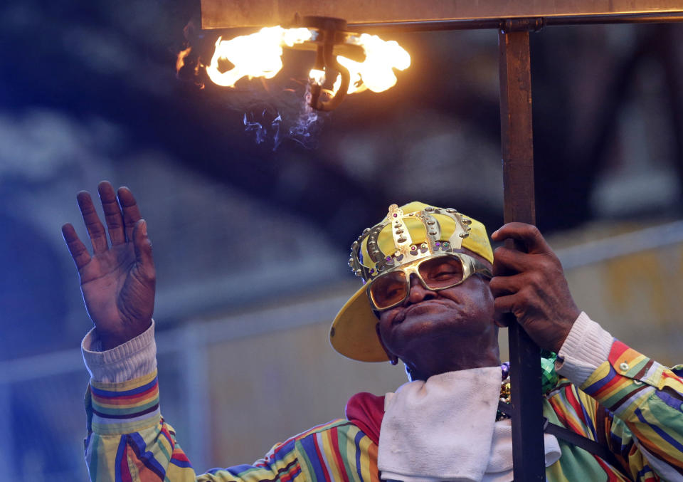 A flambeau, traditionally people who carried torches to light Mardi Gras parades, walks in the Krewe of Proteus Mardi Gras parade in New Orleans, Monday, Feb. 16, 2015. 