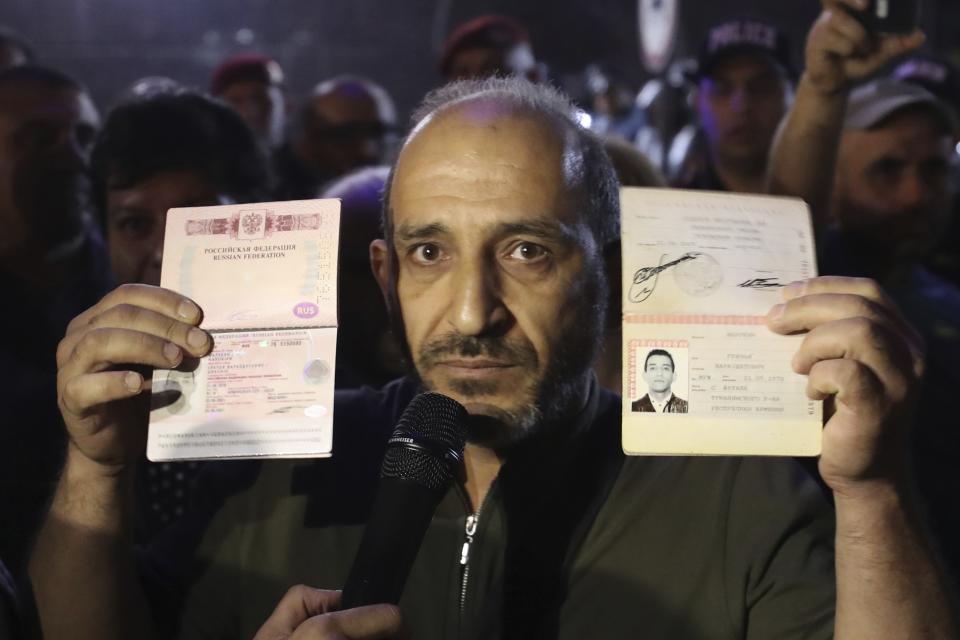 A demonstrator shows his two Russian passports, one of them for foreign trips, preparing to tear them up in protest of Russia's inaction, in the Lachin Corridor in front of the Russian Embassy in Yerevan, Armenia, Wednesday, Sept. 20, 2023. Relations between Russia and Armenia have deteriorated notably in the past year. Armenia sharply criticized Russian peacekeepers for failing to intervene in the blocking of the Lachin Corridor. (Vahram Baghdasaryan/Photolure via AP)