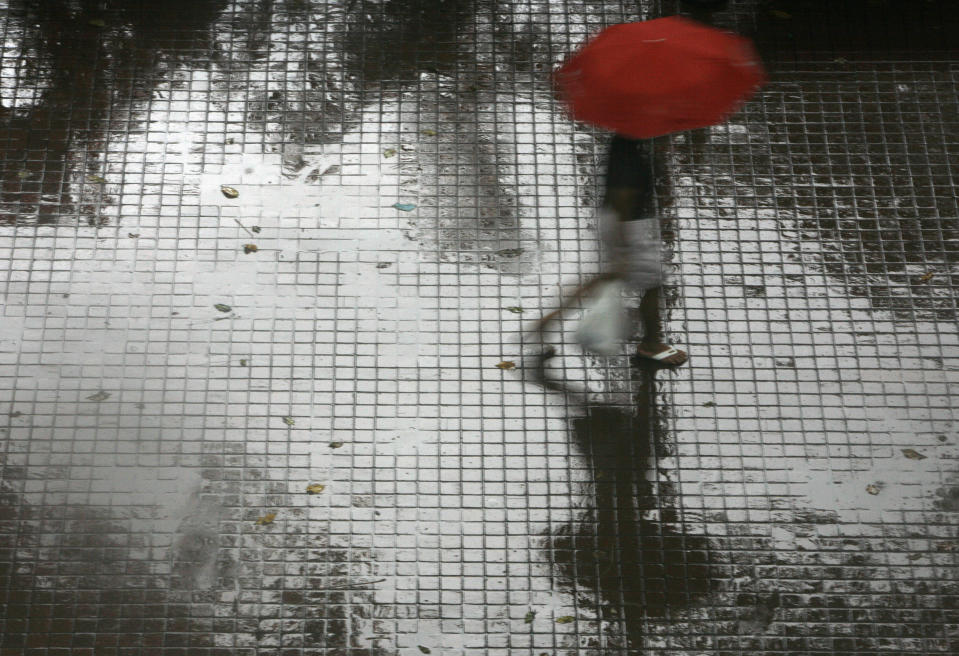 A pedestrian holds an umbrella while walking in the rain during the monsoon season in Singapore December 10, 2007.  REUTERS/Vivek Prakash (SINGAPORE)