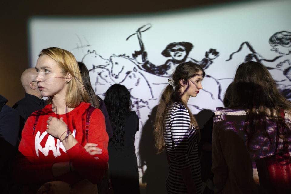 In this photo taken on Monday, March 18, 2019, visitors look at Marc Chagall illustrations for "Dead Souls", a novel by Nikolai Gogol projected on a screen during an exhibitions at the AZ Museum, in Moscow, Russia. The AZ Museum was opened in 2015 in Moscow, named after Anatoly Zverev whose portrait of a young woman was Natalia Opaleva's first purchase. (AP Photo/Alexander Zemlianichenko)