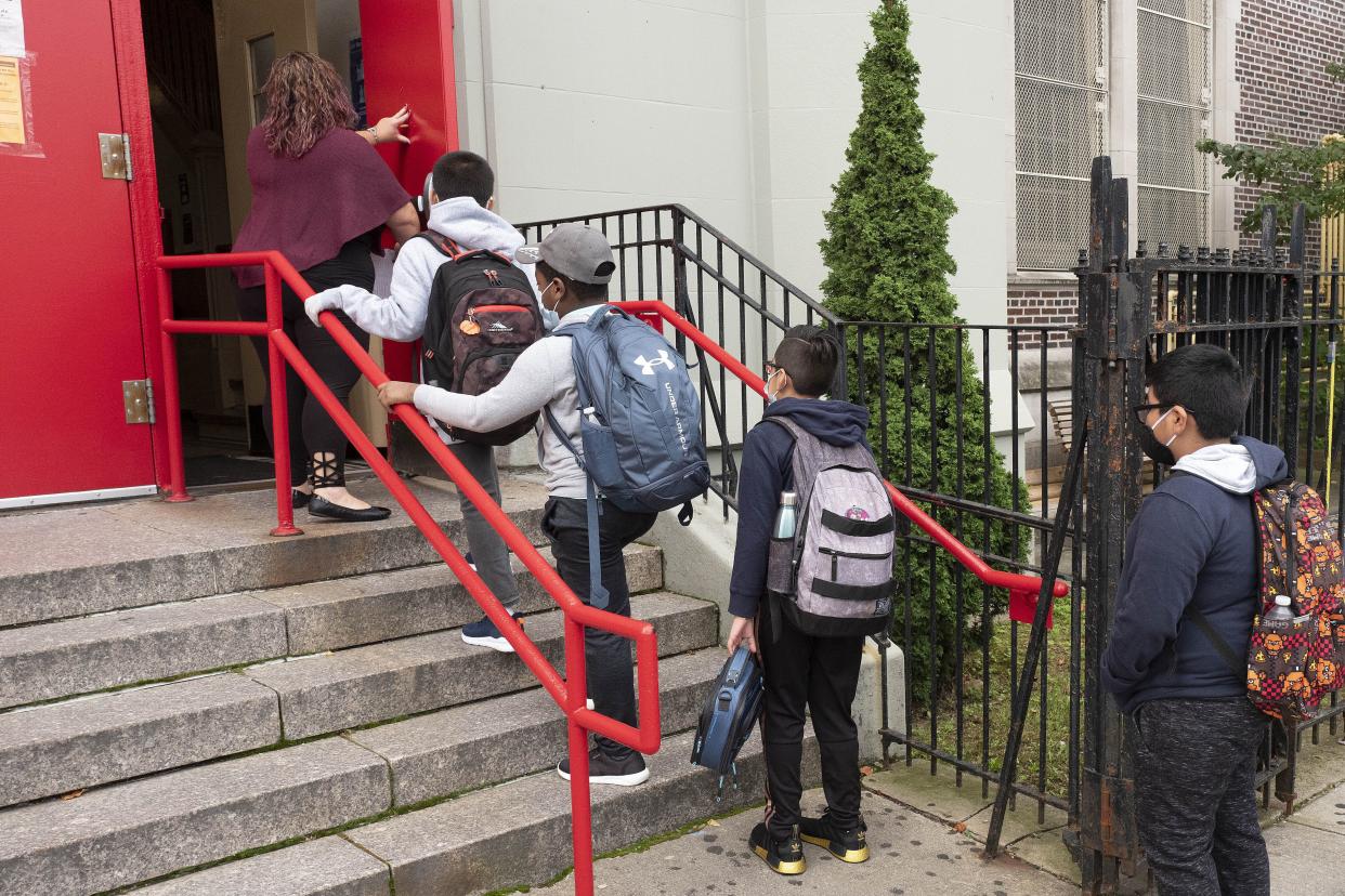 FILE - In this Sept. 29, 2020, file photo, a teacher leads her students into an elementary school in the Brooklyn borough of New York. 