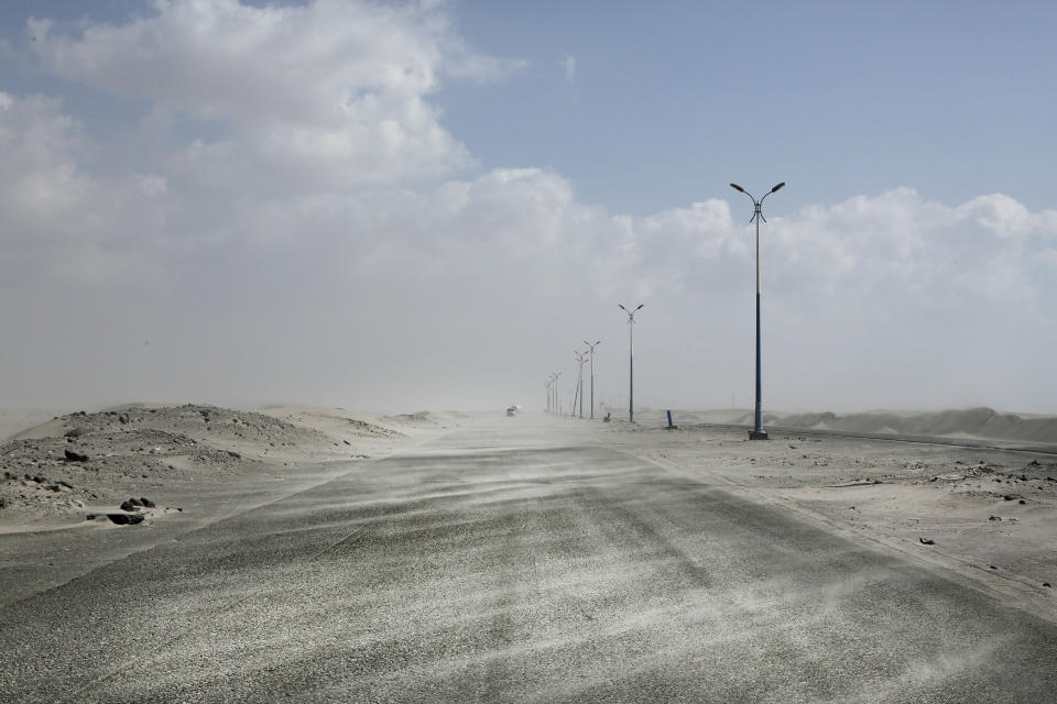 FILE - Sand drifts over an empty highway from Abyan province to the city of Aden in southern Yemen in this Feb. 15, 2018, file photo. Under secret deals with the U.S.-backed coalition, al-Qaida militants withdrew from several areas they controlled in southern Yemen in return for safe passage, integration of some militants into coalition forces and _ in at least one case _ cash. (AP Photo/Nariman El-Mofty, File)