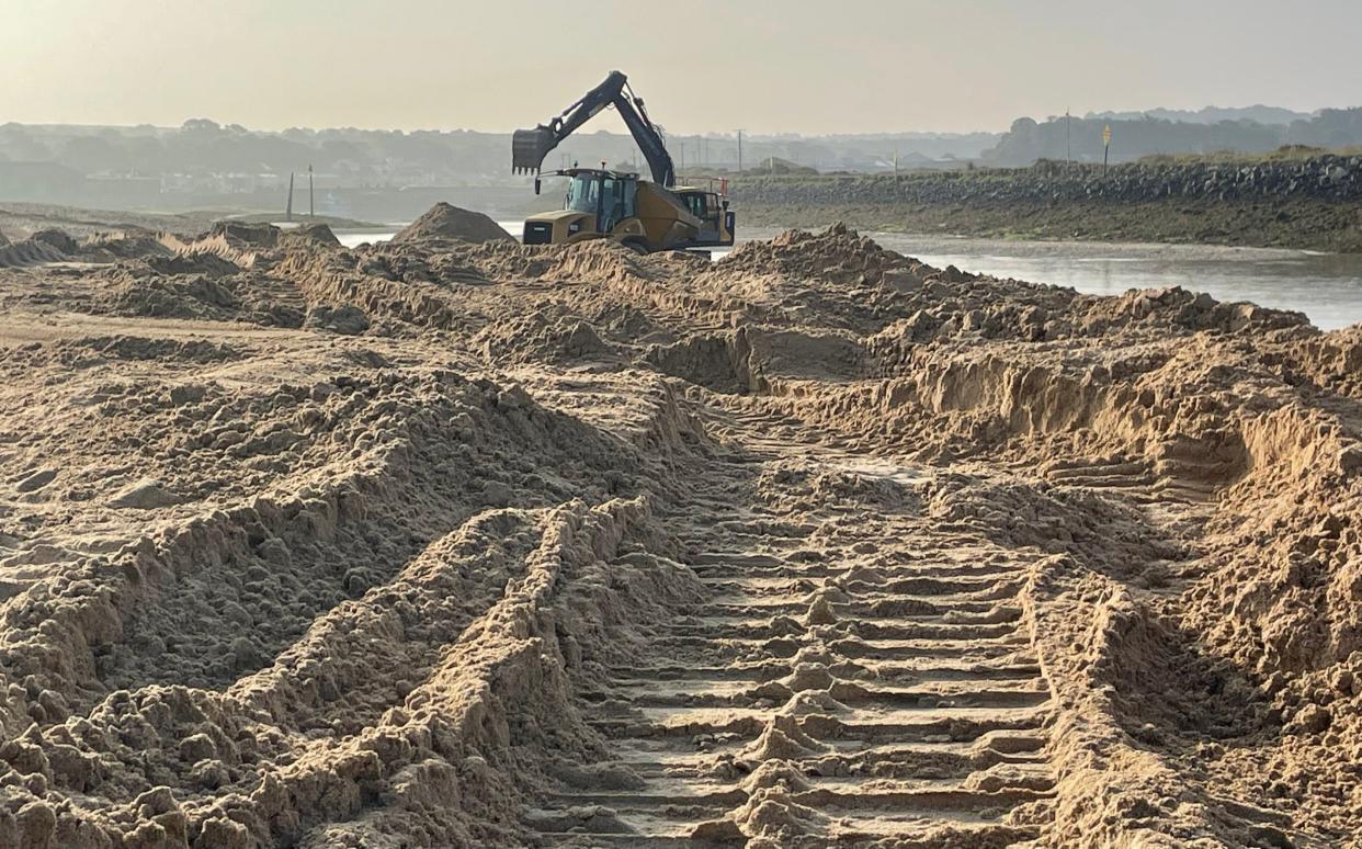 An digging vehicle and areas of excavated sand on Hayle Beach in Cornwall