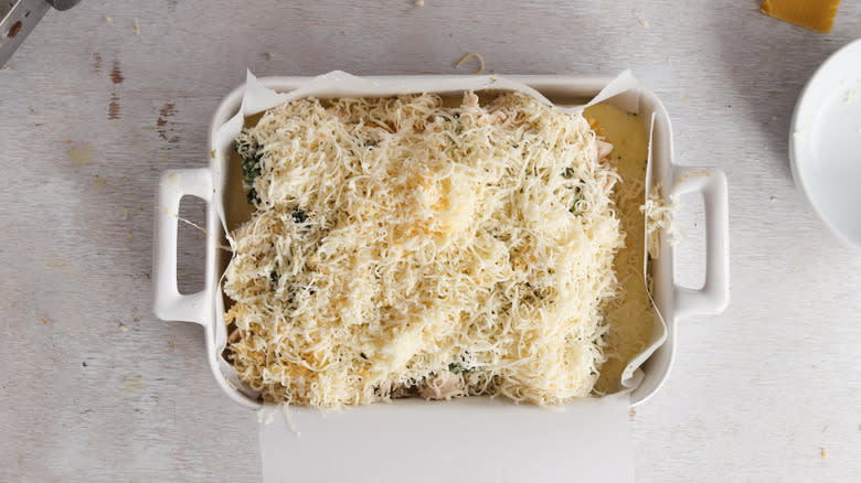 assembling chicken, spinach and cheese lasagna in baking dish