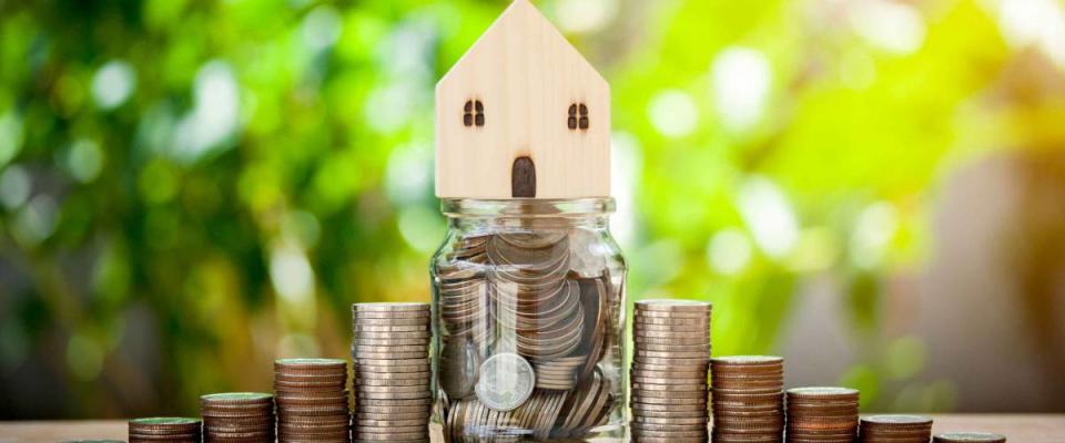 House model on coins and money in a jar for saving concept investment mortgage fund finance and interest rate home loan on bokeh background.