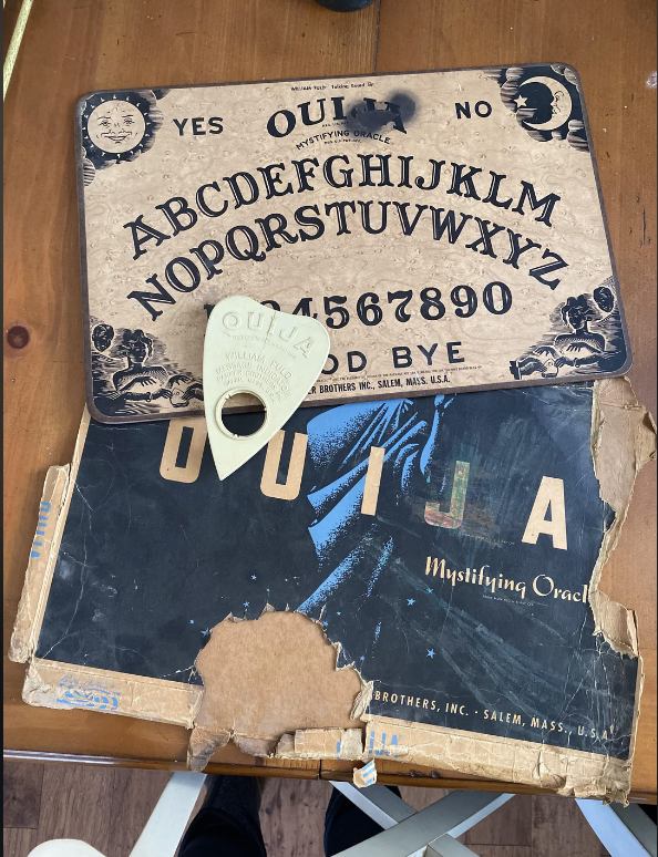 Vintage Ouija board with planchette, showing letters and numbers, worn with age and partially torn