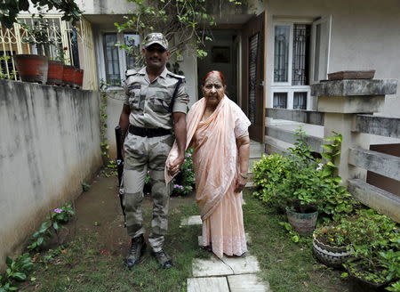 Zakia Jafri, whose late husband, a lawmaker for the Congress party which now sits in opposition, was hacked to death by a Hindu mob in riots, poses as she walks in a lawn with a security guard provided by the government at her son's house in Surat, India, September 15, 2015. REUTERS/Amit Dave