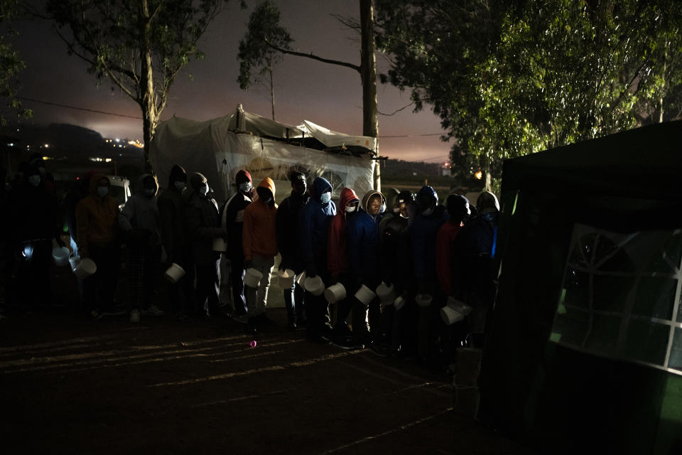 Migrants queue up to receive food in Las Raices camp in San Cristobal de la Laguna, in the Canary Island of Tenerife, Spain, Wednesday, March 17, 2021. Several thousand migrants have arrived on the Spanish archipelago in the first months of 2021. Due to the terrible living conditions and the poor quality of food and water at the Las Raices camp, some migrants have decided to leave the camp and sleep in shacks in a nearby forest instead. (AP Photo/Joan Mateu)