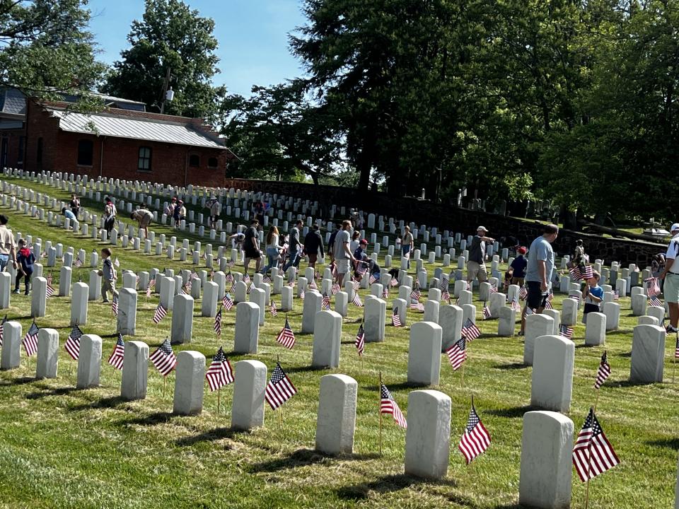 Volunteers place flags on graves at  Alexandria National Cemetery Saturday.