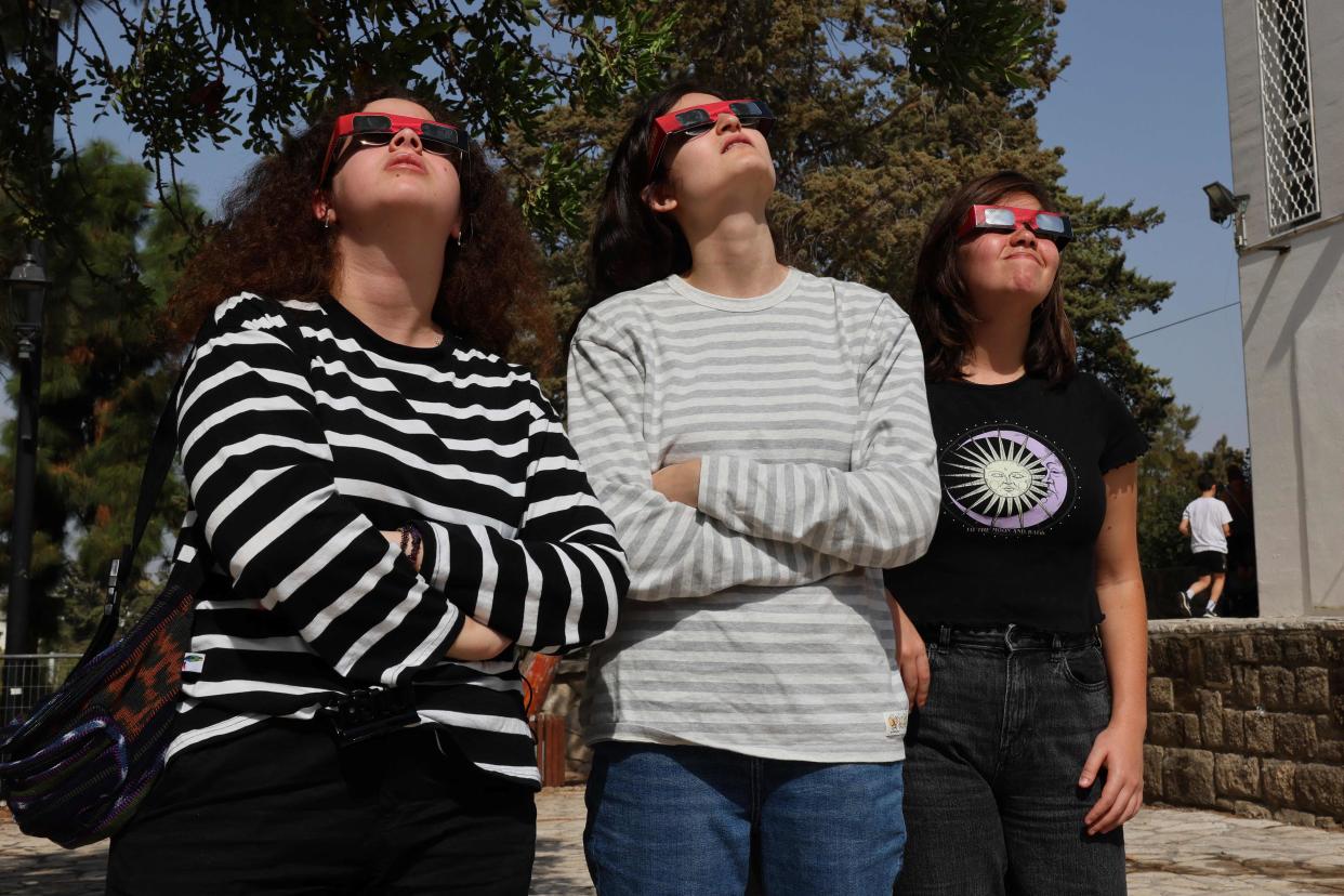 People wearing protective glasses take a glimpse of a partial solar eclipse from the Givatayim Observatory in Israel's Mediterranean coastal city of Tel Aviv on October 25, 2022.