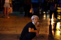 FILE PHOTO: Man smokes with a mask on his chin following the coronavirus disease (COVID-19) outbreak, during a rainfall in Beijing