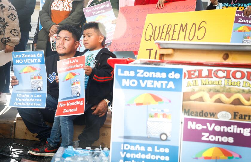 HOLLYWOOD-CA - DECEMBER 8, 2022: Jorge Cruz, left, and his son Luis, 5, gather with street vendors and supporters on Hollywood's Walk of Fame to demonstrate against an LA city ordinance created of eight citywide no vending zones, on Thursday, December 8, 2022. Cruz and his wife sell fruit in Santa Monica and say they are often harassed by police. (Christina House / Los Angeles Times)